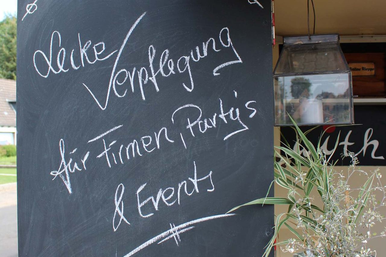 Tafel mit Aufschrift "Leckere Verpflegung für Firmen, Partys & Events"" am Foodtruck in Kaltenkirchen 