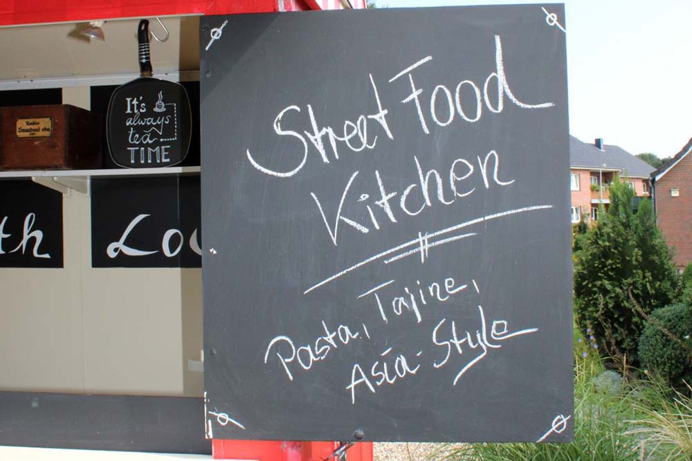 Tafel mit Aufschrift "Streetfood-Kitchen" am Foodtruck in Kaltenkirchen 