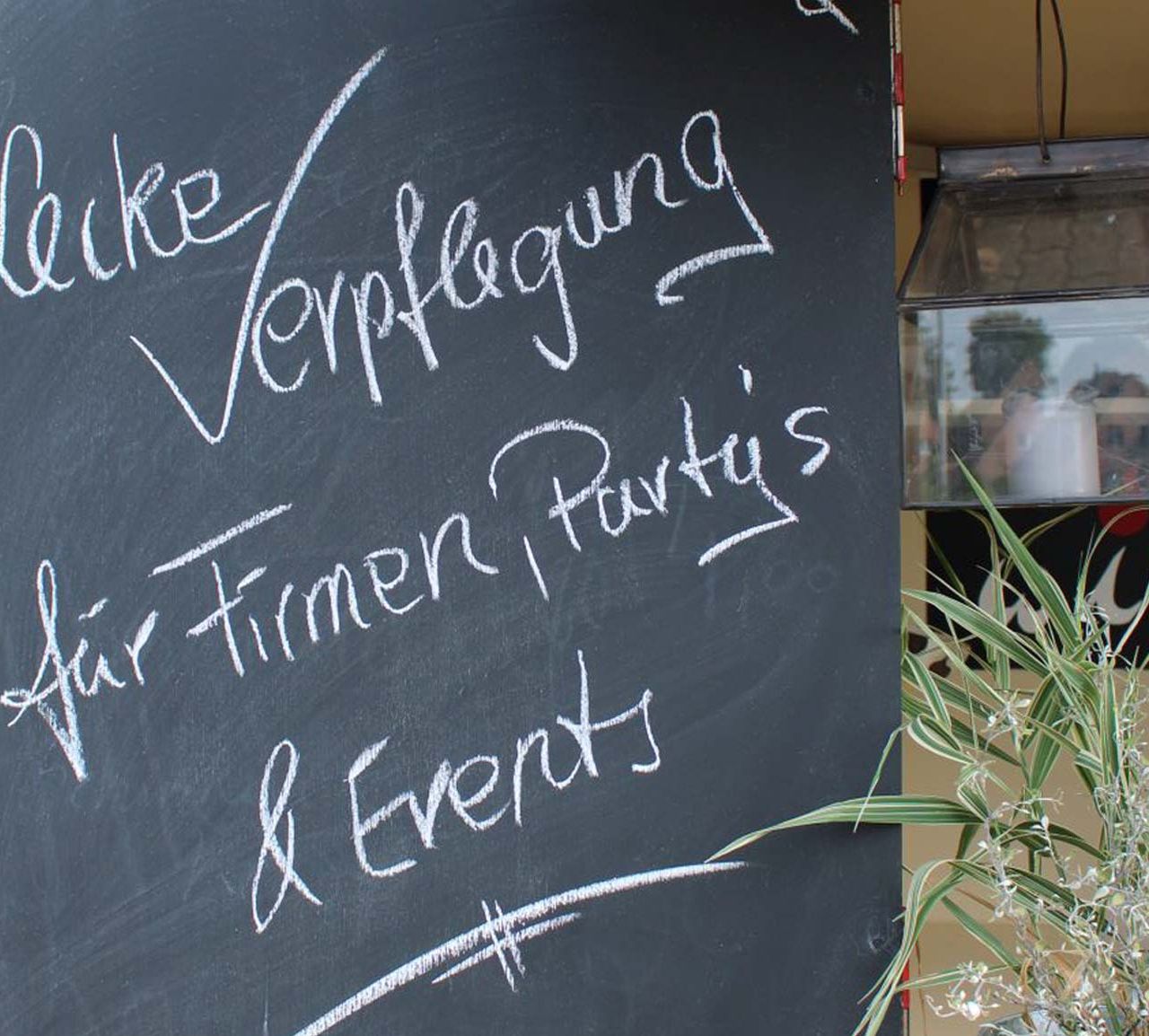 Tafel mit Aufschrift "Leckere Verpflegung für Firmen, Partys & Events"" am Foodtruck in Kaltenkirchen 