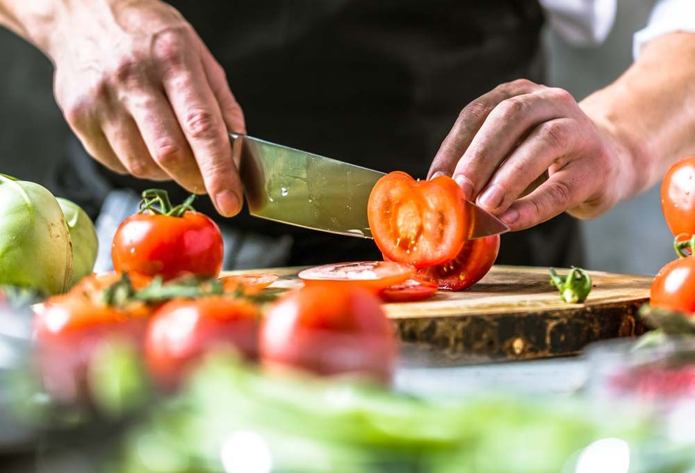 Koch schneidet Tomaten für ein Catering